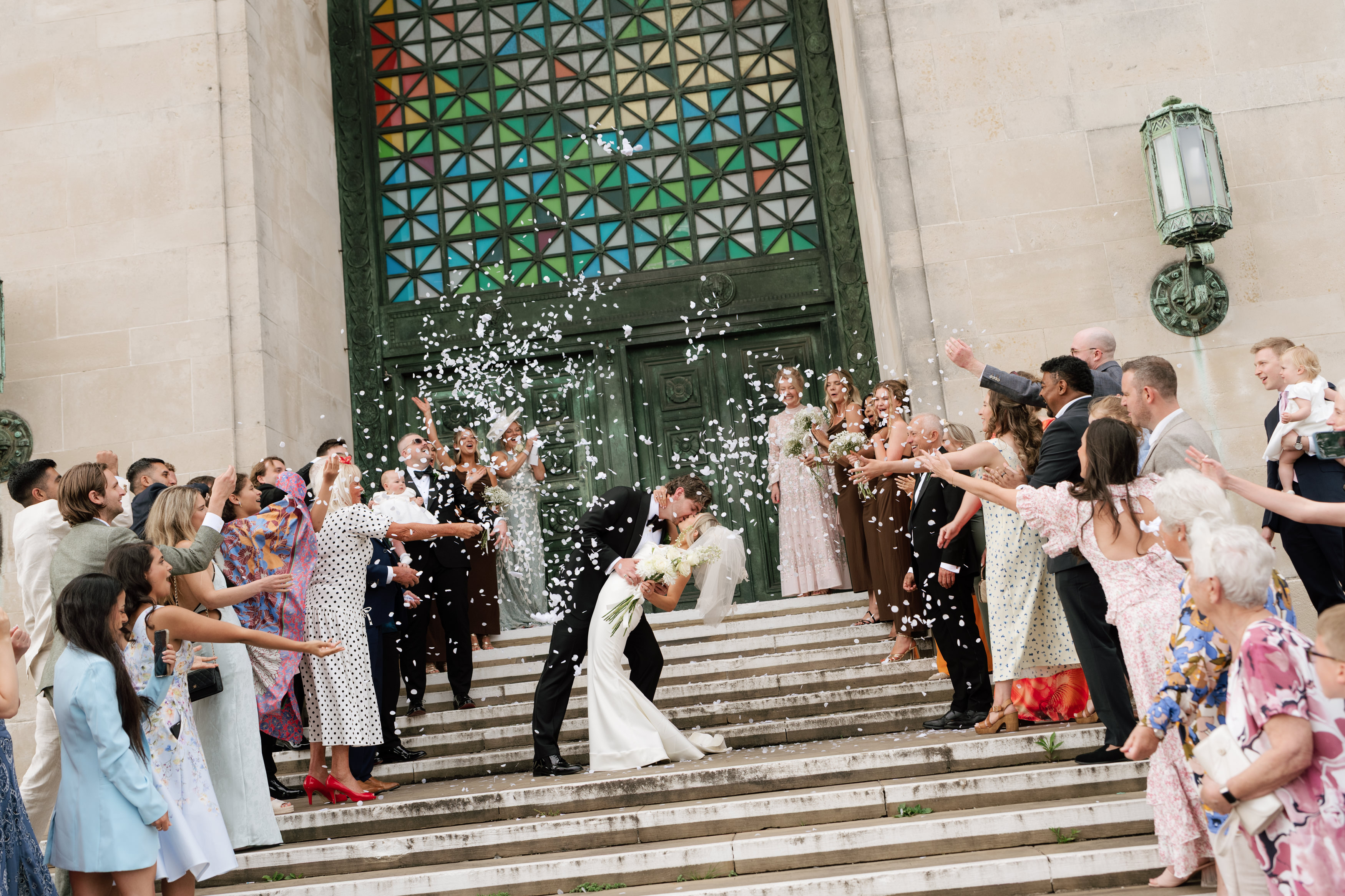 Guests throwing confetti as Hannah and Andrew kiss on the Guildhall steps.