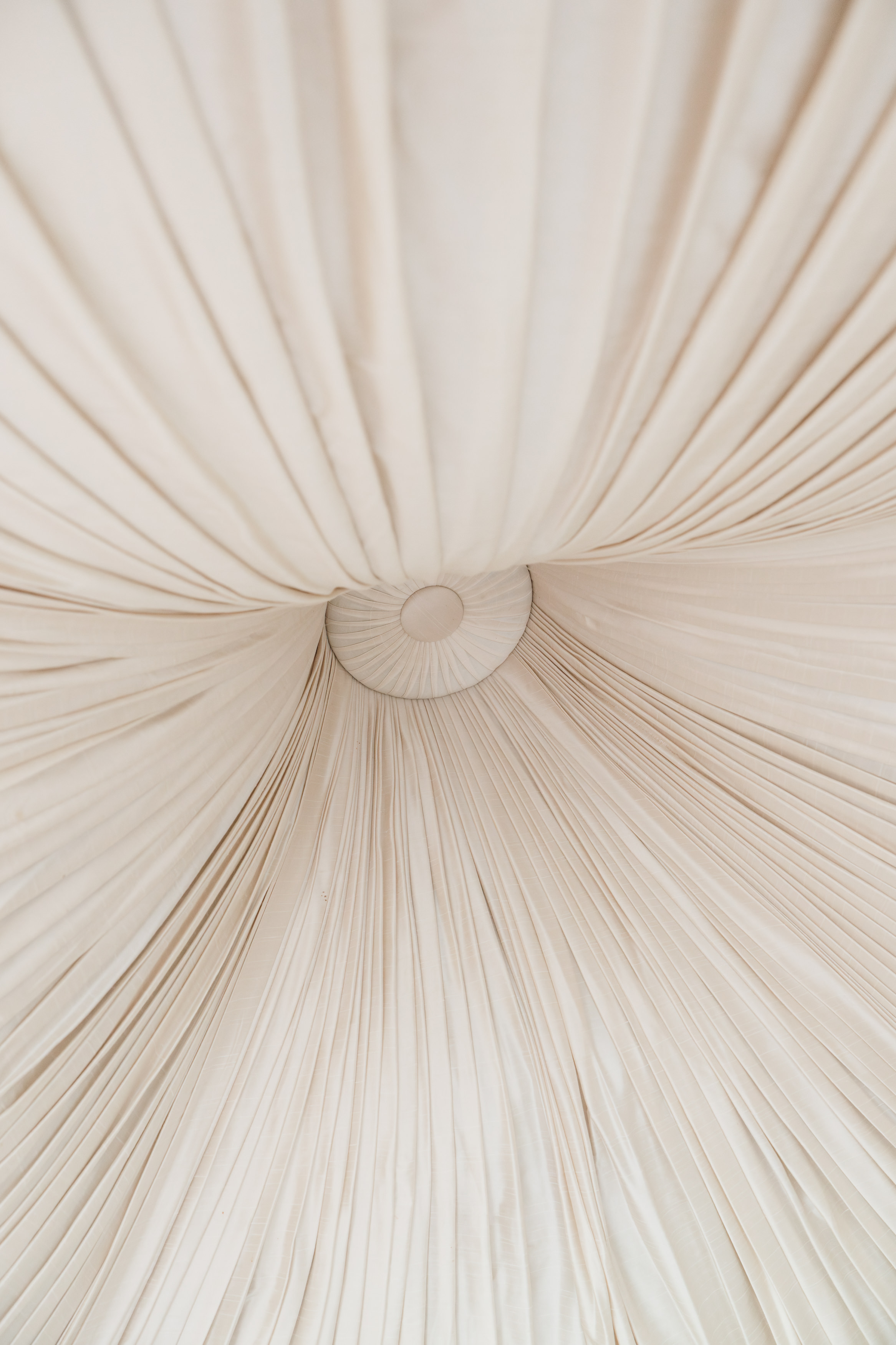 Cream-coloured fabric is pleated and hangs out from a circle in the middle of the ceiling, making the room look like it’s inside a tent.
