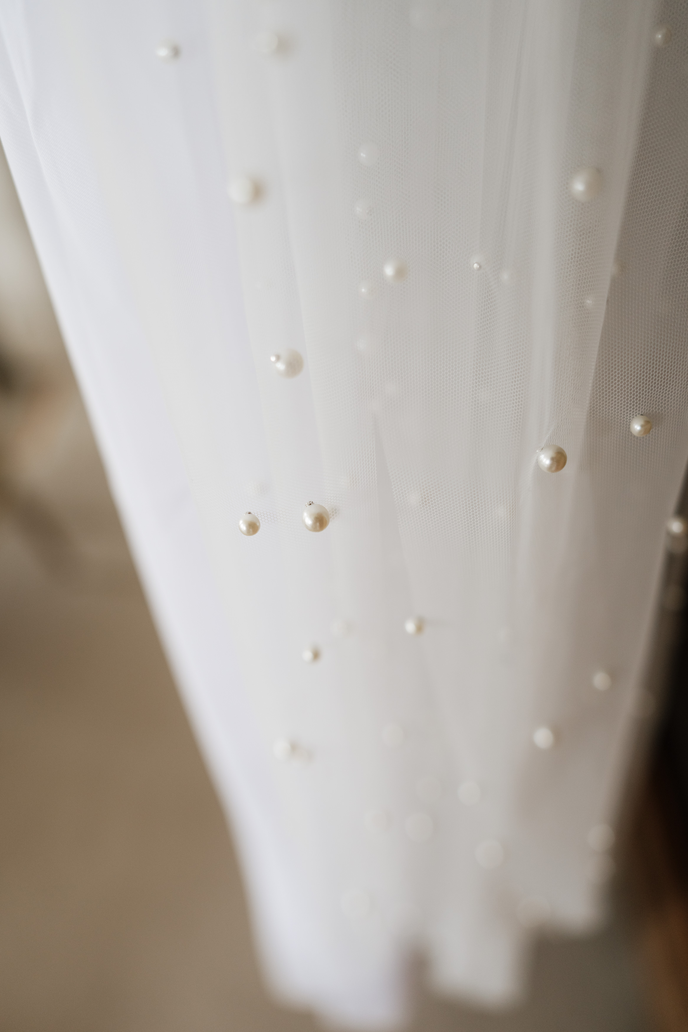 A close-up look at some thin, white fabric with little pearl-like beads spread out evenly across it.