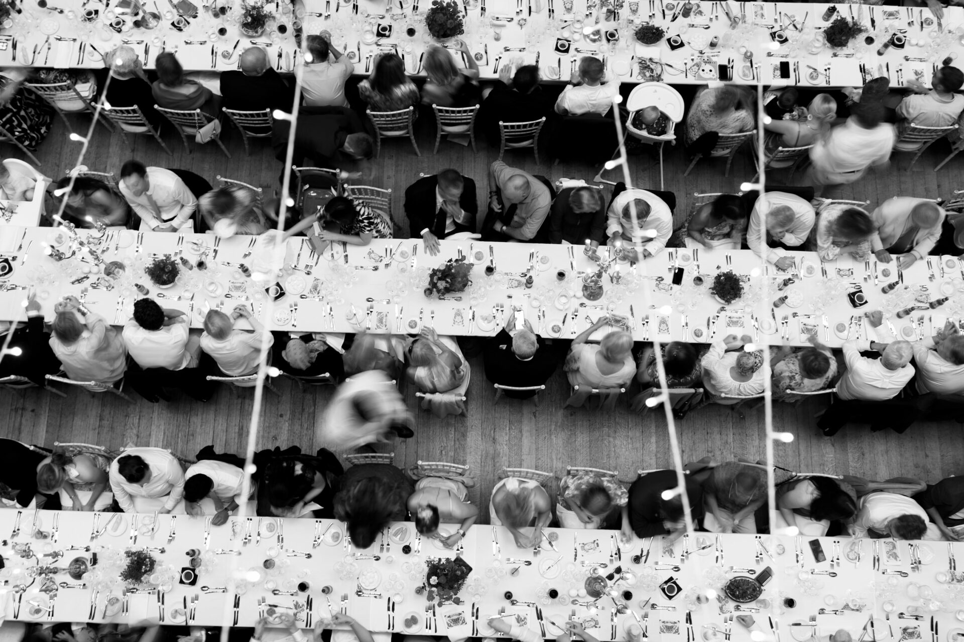A bird's-eye view of people sitting at long tables beside each other at an event.